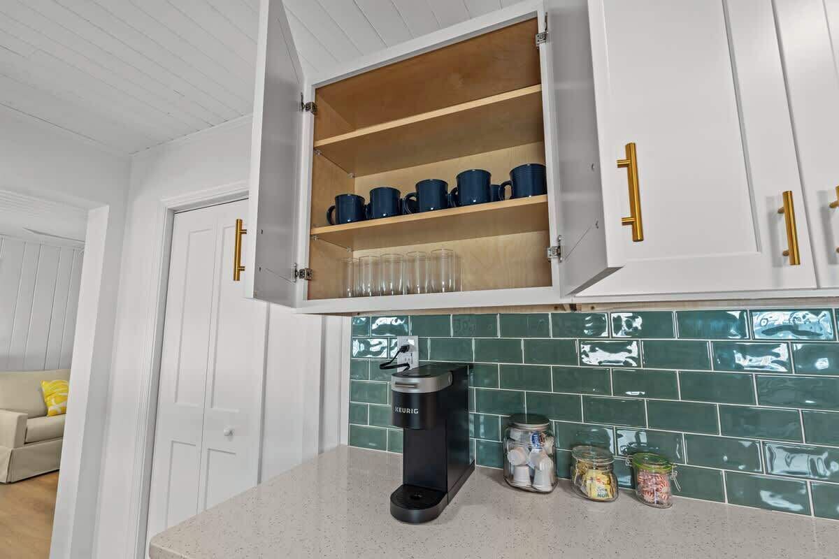 A kitchen with white cabinets, a coffee machine, and jars on the counter.