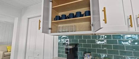 A kitchen with white cabinets, a coffee machine, and jars on the counter.