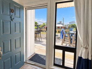A room with a sliding glass door leading to an outdoor deck with chairs and tables. - Captain Chris at South Winds | Across from Beach + Walk to Gulf Shores Fun (Gulf Shores)