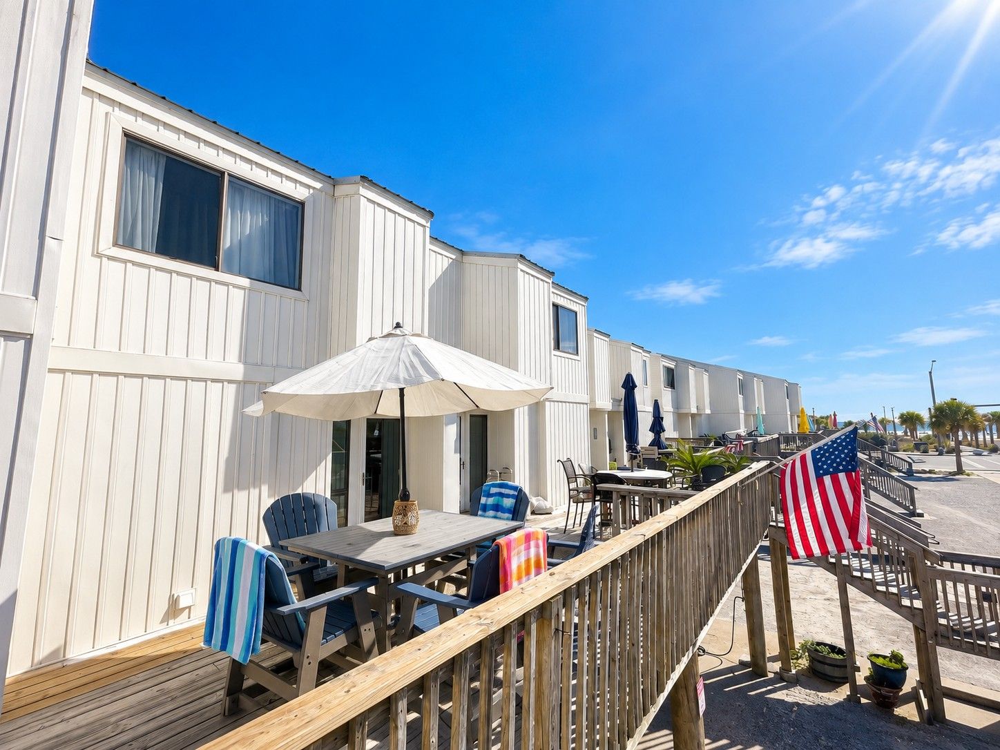 Une rangée de maisons mobiles dotées de patios extérieurs, d’une terrasse en bois et d’un drapeau américain.