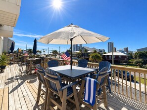 Eine Terrasse im Freien mit Holzdeck, Tischen, Stühlen und Sonnenschirmen.