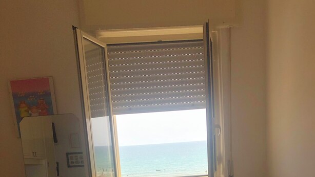 A bedroom with a bed, a chair, a desk, and a window with a view of the sea. - House by the sea (Lido Chiatona-Stazione di Palagiano)