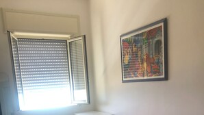 A room with a bed, a desk, a chair, and a window with blinds. - House by the sea (Lido Chiatona-Stazione di Palagiano)