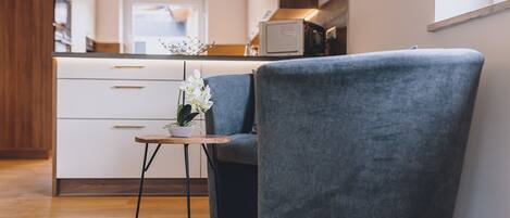 A modern kitchen with white cabinets, a wooden countertop, and a small table with a potted orchid.