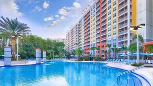 Un hôtel doté d’une grande piscine, de nombreux balcons et d’une végétation luxuriante.
