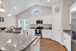 A modern kitchen with white cabinets, granite countertops, a large island, stainless steel appliances, and a skylight. - Inlet Retreat Near Golf, River & Ocean Boat access (Murrells Inlet)