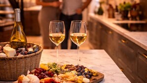 En marmor bordplade med et charcuteri fad, to glas hvidvin og en flaske vin.