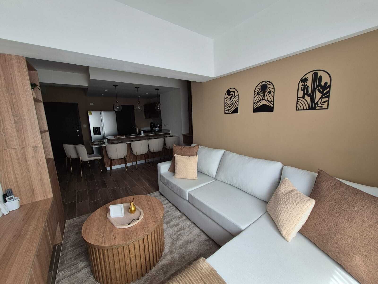 A modern living room with a sofa, a coffee table, and a dining area with chairs.