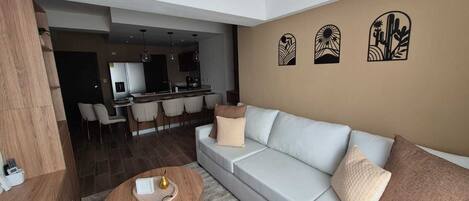A modern living room with a sofa, a coffee table, and a dining area with chairs.