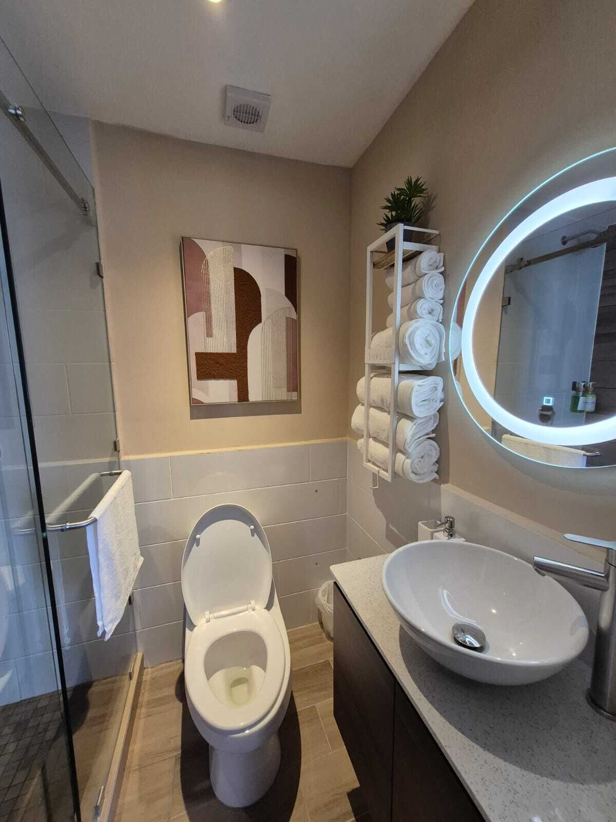 A modern bathroom with a toilet, sink, and a wall-mounted mirror.