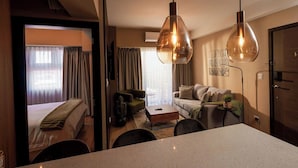 Une chambre d’hôtel comprenant un lit, un canapé, une table basse et un coin repas avec des chaises.
