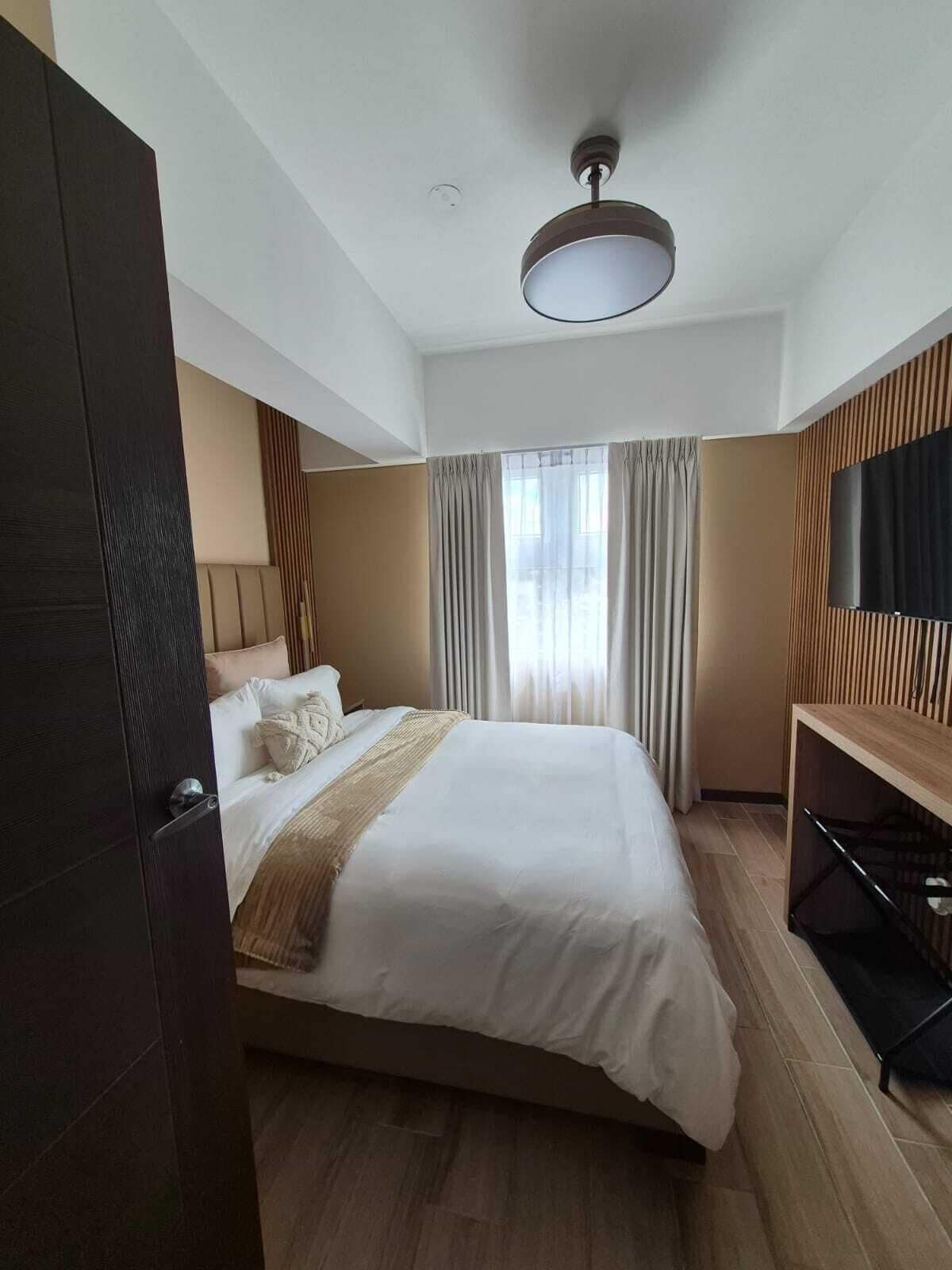 Ein modernes Hotelzimmer mit einem großen Bett, einem Flachbildfernseher und einem Deckenventilator.