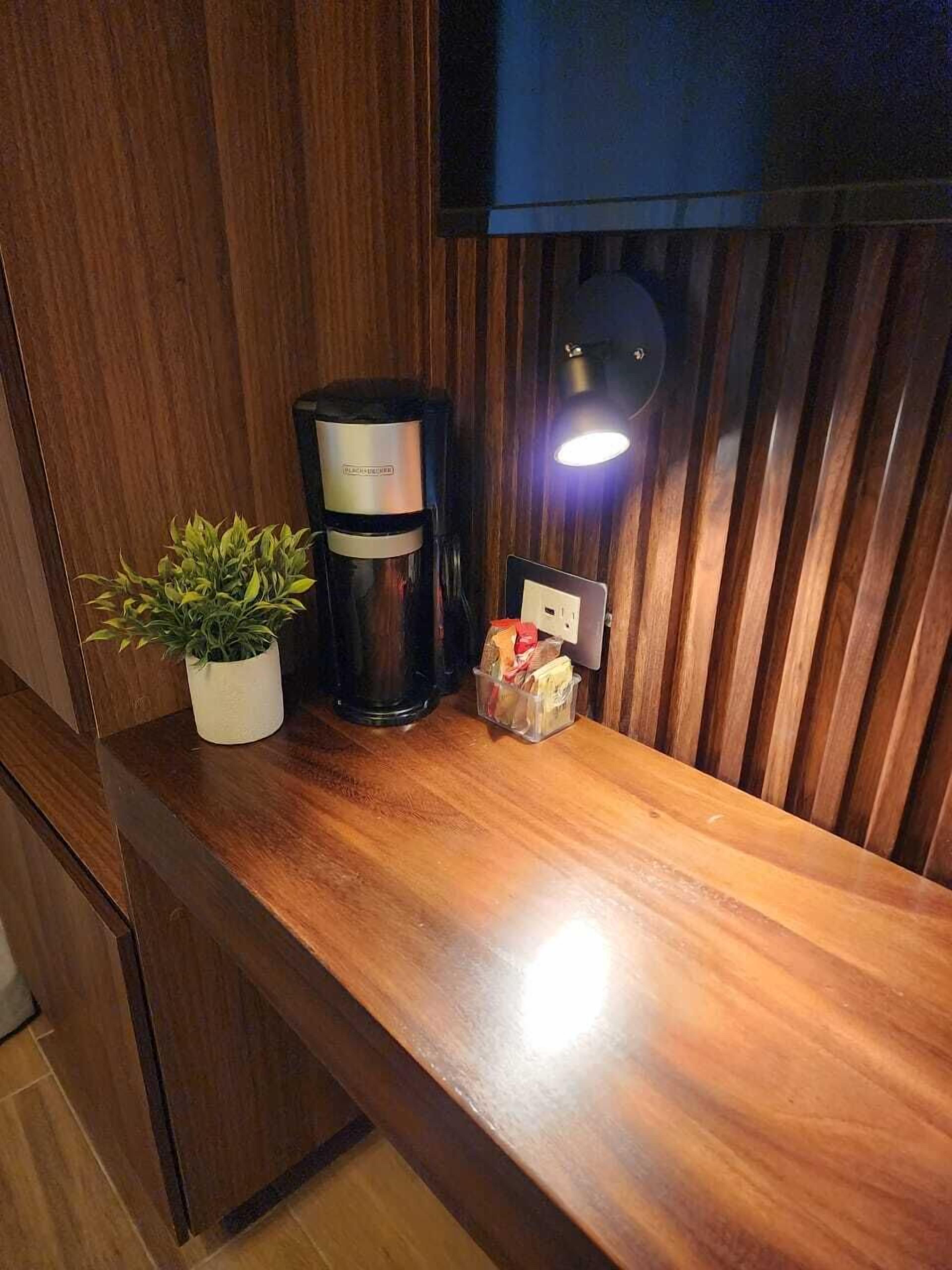 A wooden countertop with a coffee maker, a potted plant, and a small box of tissues.