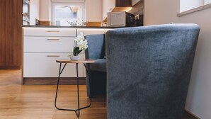 Une cuisine moderne avec des meubles blancs, un plan de travail en bois et une petite table sur laquelle est posée une orchidée en pot.