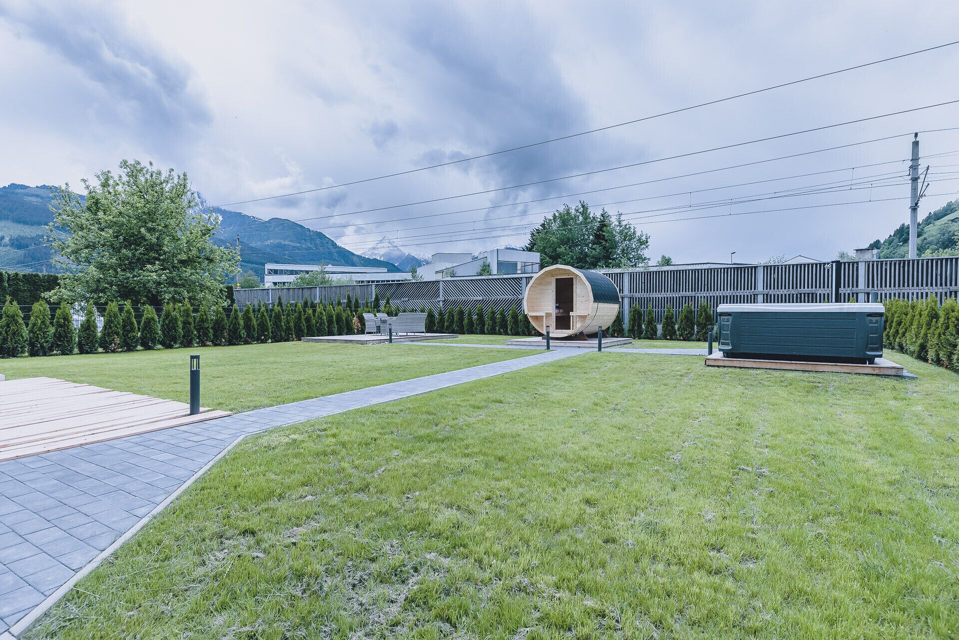 Un bâtiment moderne à la structure cylindrique, situé au centre et entouré d’une pelouse bien entretenue et d’un chemin pavé.