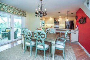 Uma sala de jantar com mesa e cadeiras de madeira, um candelabro e vista para o exterior.