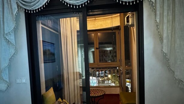 Ein Wohnzimmer mit einer Couch, einem kleinen Tisch und Blick durch eine Glastür in einen Küchenbereich.