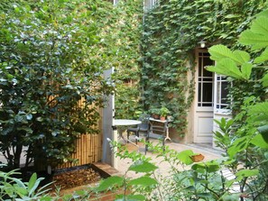 Ein Innenhof mit Holzzaun, Tisch mit Stühlen und Topfpflanzen.