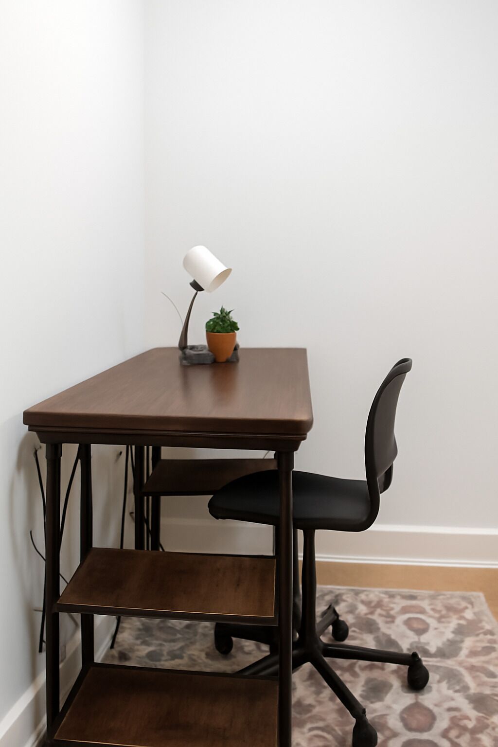 A corner desk with a chair, a lamp, and a small plant.