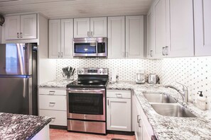 A modern kitchen with stainless steel appliances, white cabinetry, and a granite countertop. - Snowcrest Classic Crested Butte! 2 Bed, 2bath (Crested Butte)