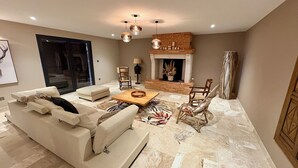 A modern living room with a sofa, coffee table, and chairs. There is a fireplace with a brick surround and a ceiling light fixture. - Le Clos de Galou, Authenticity, Comfort, Nature (Aucamville)