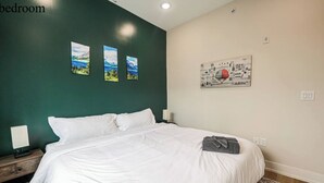 Ein Schlafzimmer mit einem großen Bett, einem Nachttisch, einer Wandlampe und drei gerahmten Bildern.