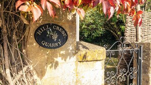 A stone sign with "HILL CREST QUARRY" engraved on it, surrounded by autumn foliage and a wrought iron gate. - Beautiful 2BD Cottage in the Cotswolds (Bourton-on-the-Hill)
