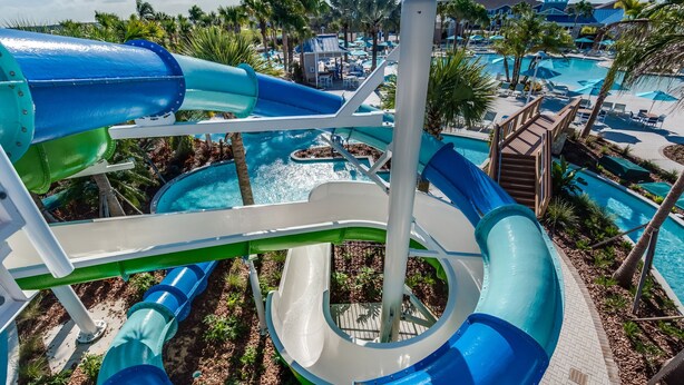 Un parque acuático con múltiples toboganes y piscinas, rodeado de palmeras y zonas de descanso.