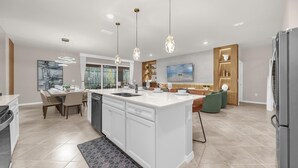 Cocina moderna con una isla central, iluminación colgante y un comedor con vistas.