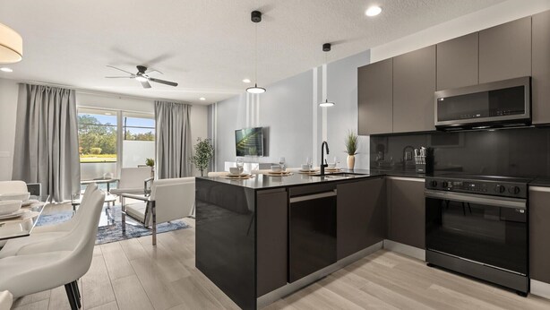 A modern kitchen with dark cabinetry, a built-in oven, and a large island with a sink.