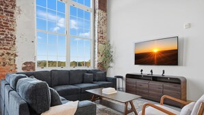A modern living room with a sectional sofa, a coffee table, and a TV mounted on the wall.