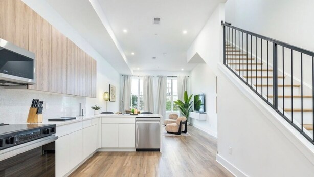 A modern kitchen with white cabinets, a built-in oven, and a black range hood.