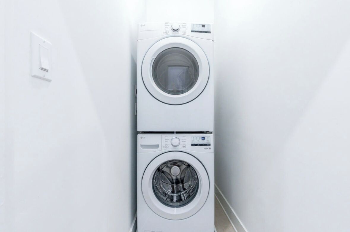A stacked washer and dryer unit in a hallway.