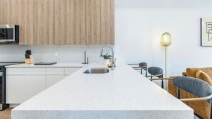 A modern kitchen with a central island, white cabinetry, and a wooden accent wall.
