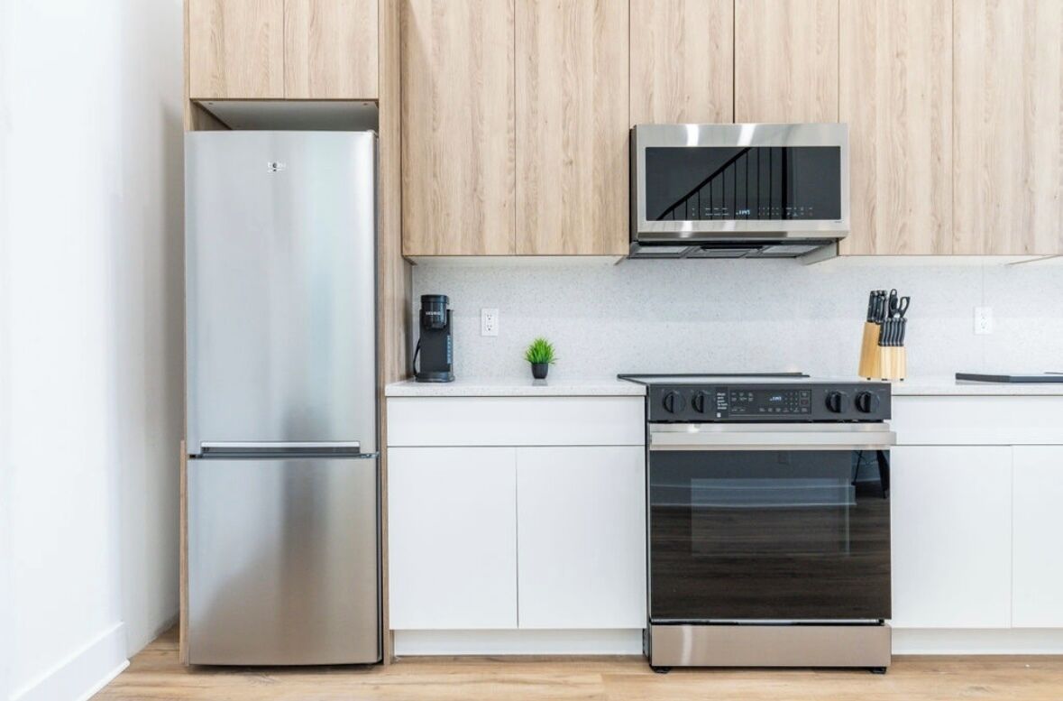 A modern kitchen with stainless steel appliances, wooden cabinets, and a small potted plant.