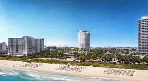 Ein Hotel am Strand mit mehreren Hochhäusern, einem Sandstrand und blauem Himmel.