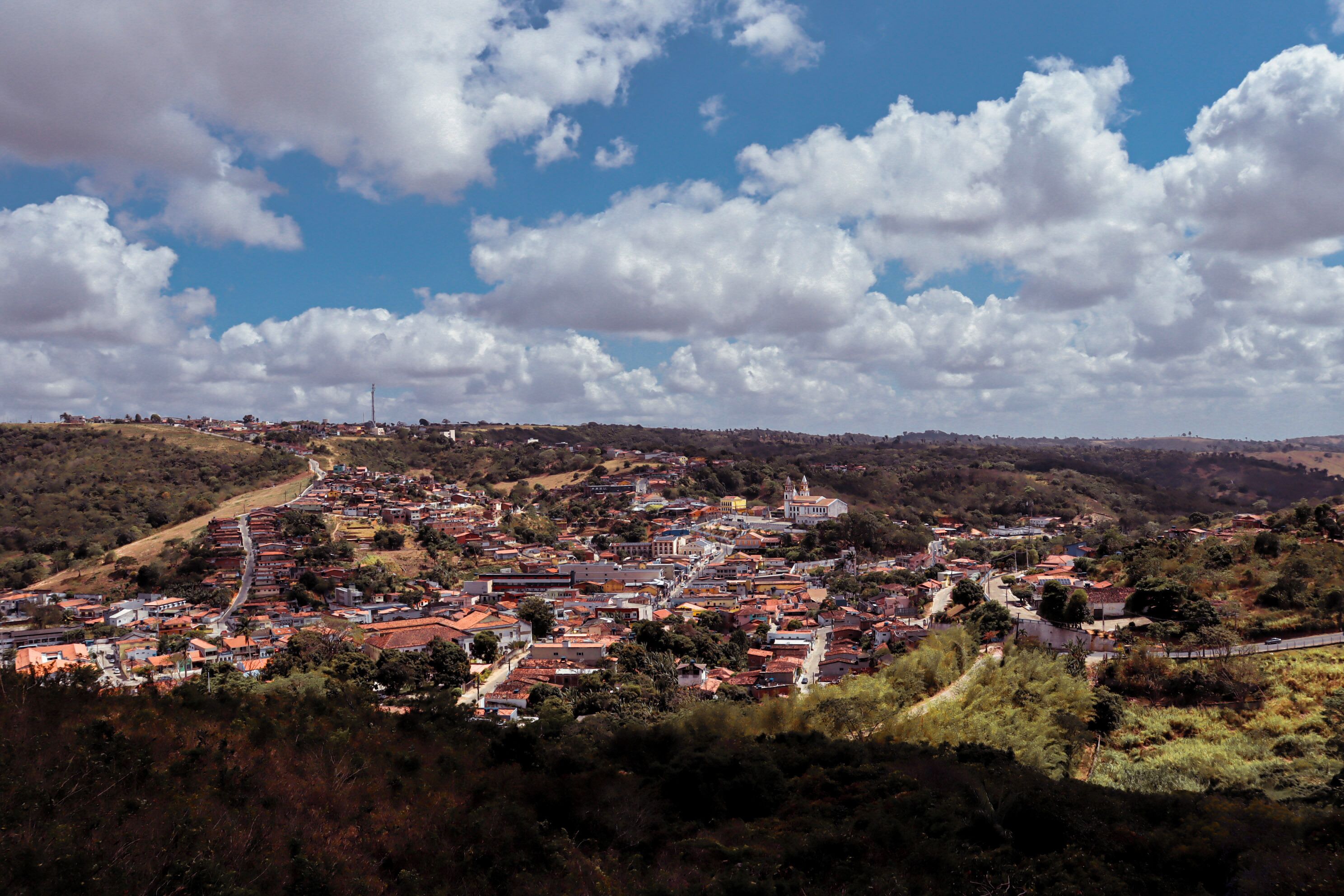 A town with a central square, surrounded by buildings and hills.