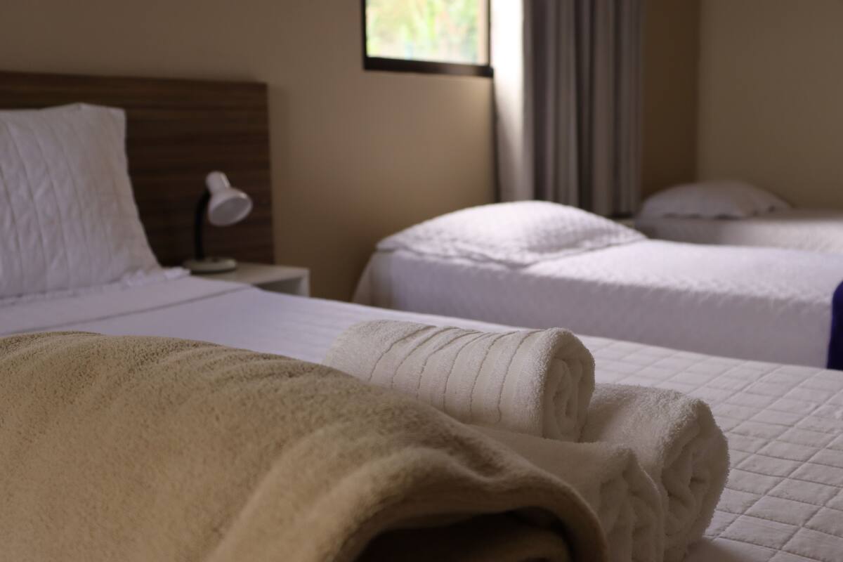 A hotel room with a bed, a bedside lamp, and a window with curtains.