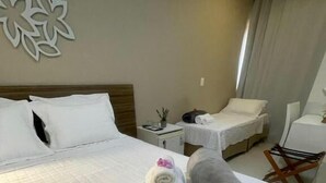 Ein Hotelzimmer mit einem großen Bett, zwei Nachttischen, einem Sessel und einer Wanddekoration.