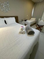 Habitación de hotel con una cama grande, dos mesitas de noche, una silla y un adorno en la pared.