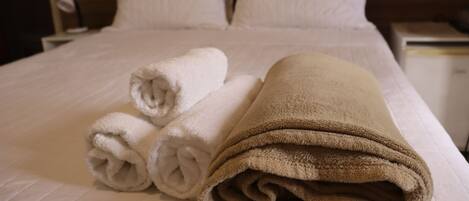 A neatly made bed with white and beige towels.