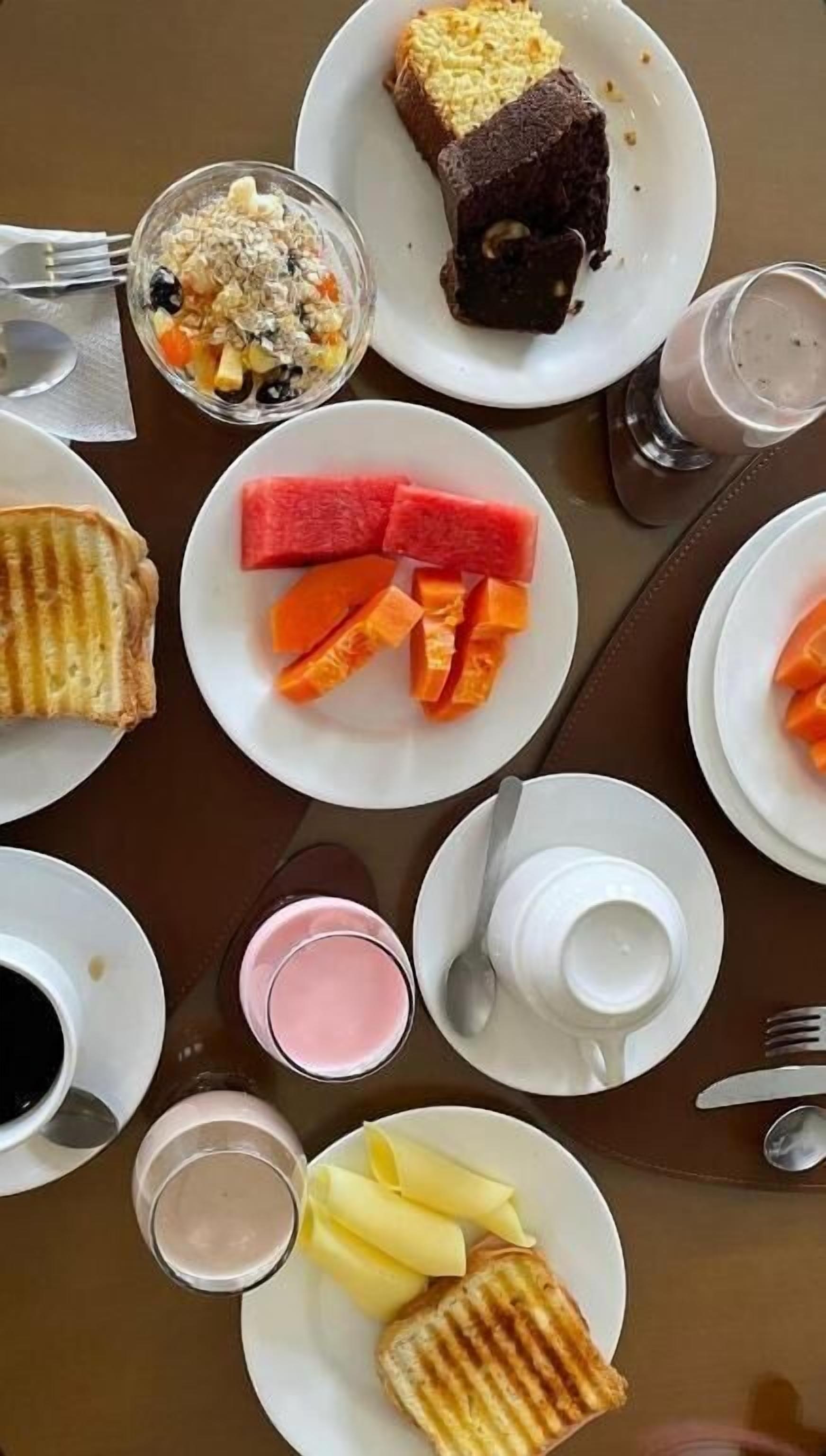 A breakfast setting with various dishes including toast, watermelon, and a fruit bowl.