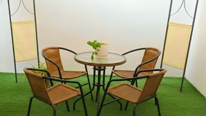 A round table with four wicker chairs, surrounded by artificial green grass. - Casa Estancia Jaén * Jaén Country House *. (Jaén)