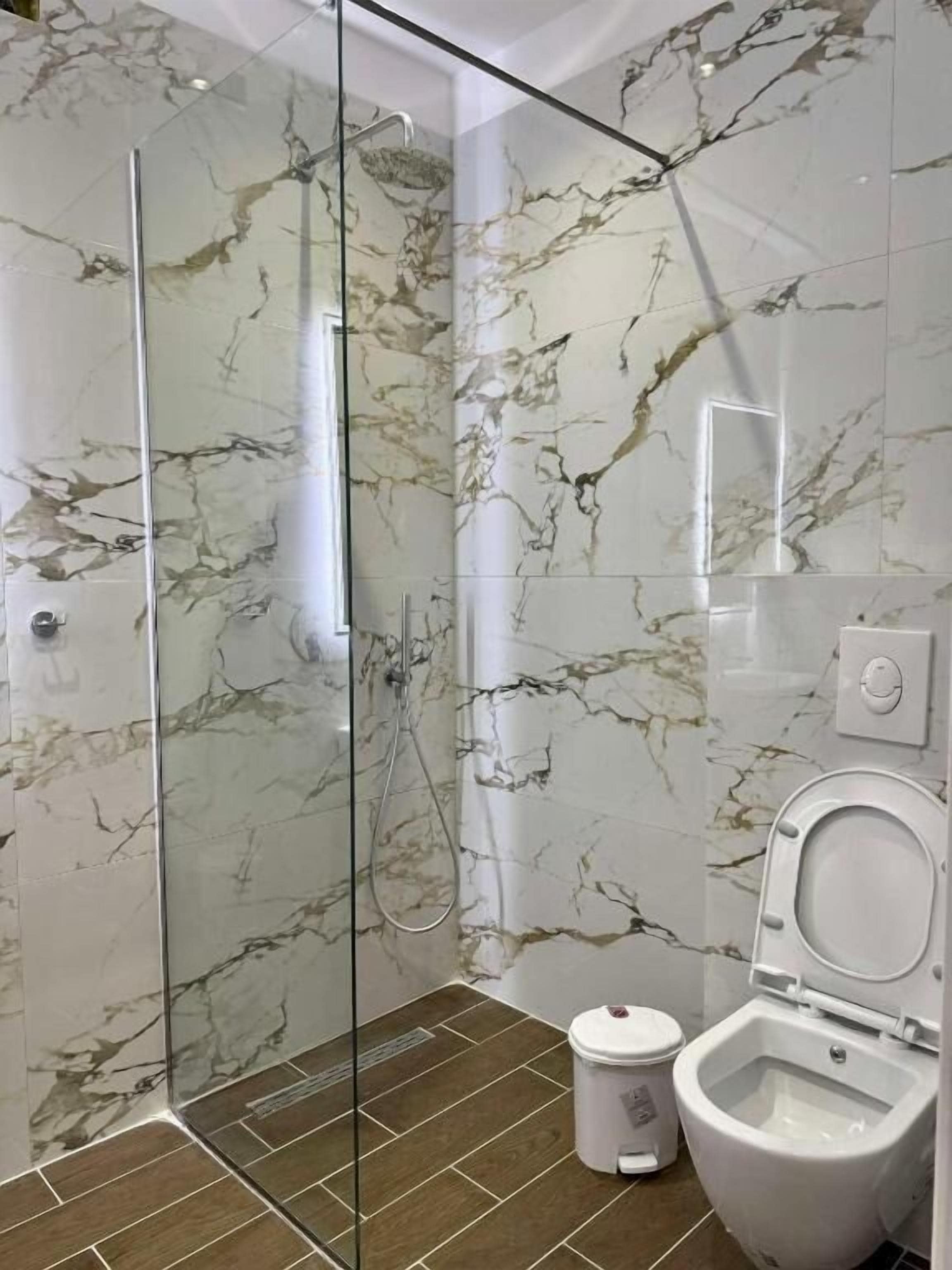 A modern bathroom with a glass-enclosed shower, a toilet, and a bidet.