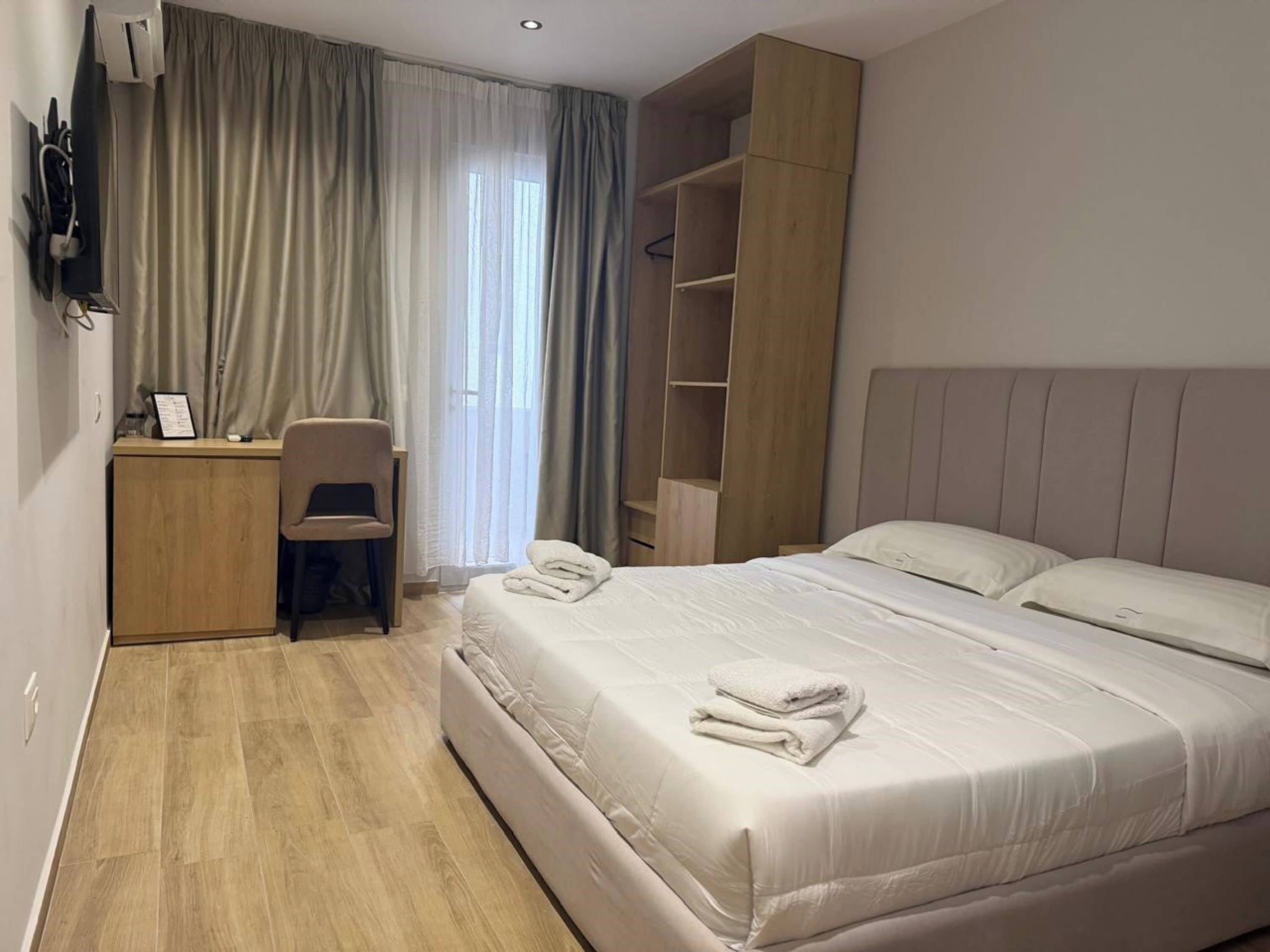 Una habitación de hotel con cama, escritorio, silla, televisor y armario.