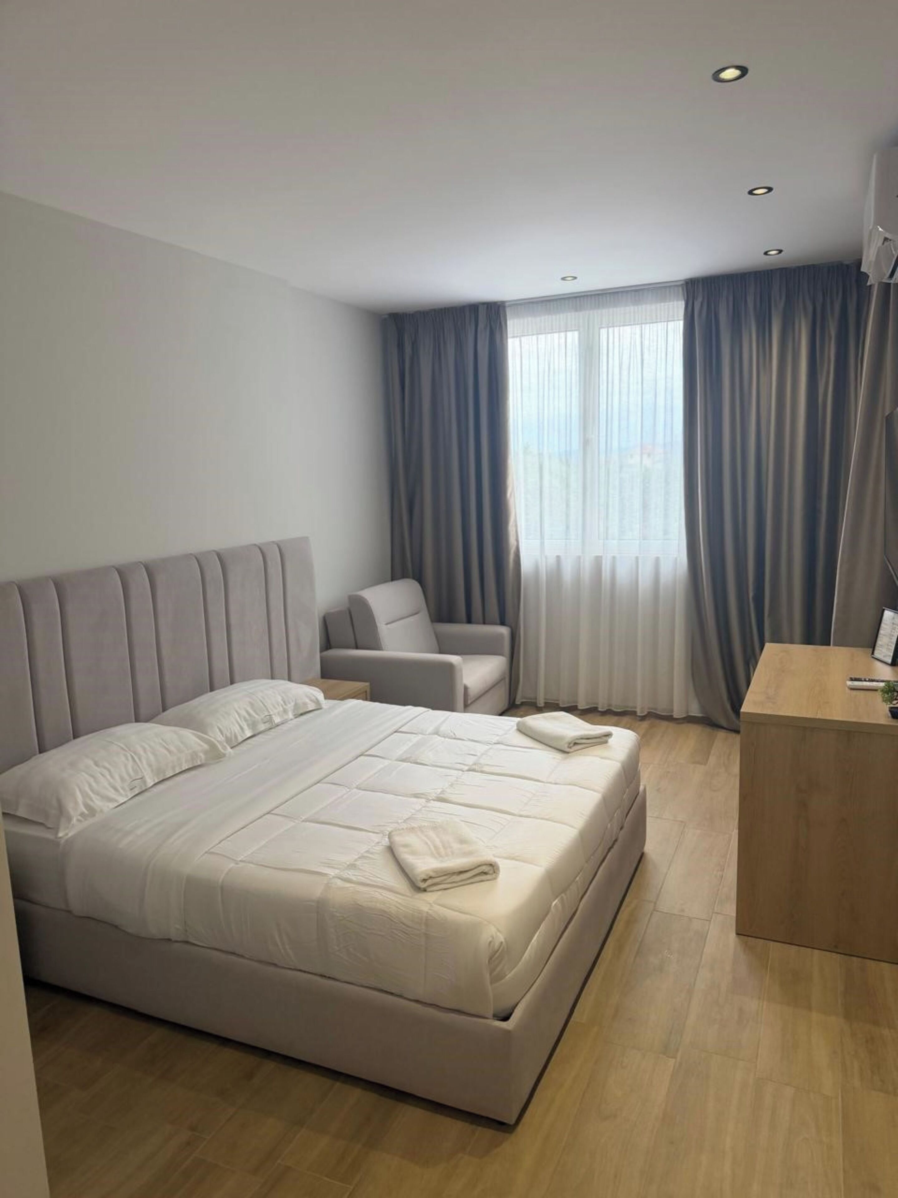 A modern hotel room with a large bed, a seating area, and a desk.