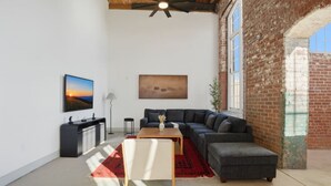A modern living room with a sectional sofa, a coffee table, and a TV. - Unique, Historic 2BD Apt w/ Study (Greenville)