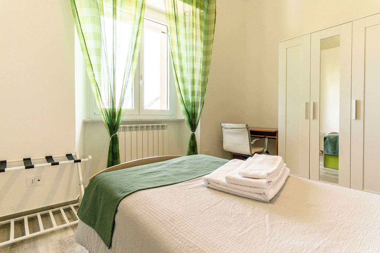 Une chambre à coucher avec un lit, un radiateur, une chaise et une armoire.