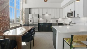 A modern kitchen with white cabinets, stainless steel appliances, and a large island.
