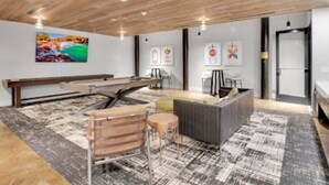 Un interior moderno con techo de madera, mesa de billar, zona de bar y un conjunto de asientos.